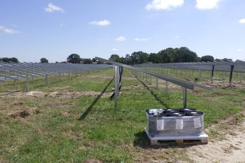 Rammpfosten und Mustertisch einer PV-Freiflächenanlage im Bau, daneben Module auf einer Palette