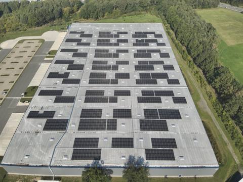 Luftbild eines Hallendachs mit mehreren Modulfeldern zwischen Lichtkuppeln