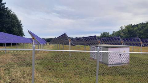 The same section with tracker rows, a fence in the foreground and a station