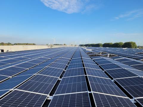 Flat-roof system with long rows of modules on east-west mounting under a blue sky