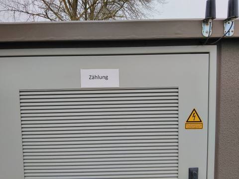 Transformatorstation mit großem Lüftungsgitter und Warnzeichen für elektrische Spannung
