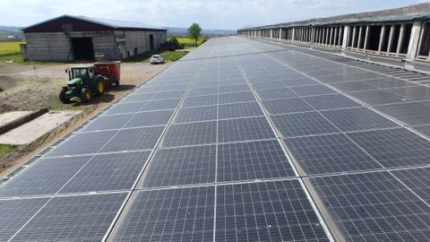 Rooftop system on an agricultural building, with a barn and a tractor in the background